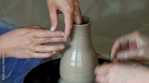 Hands of two people create pot, potter's wheel. Teaching pottery photo