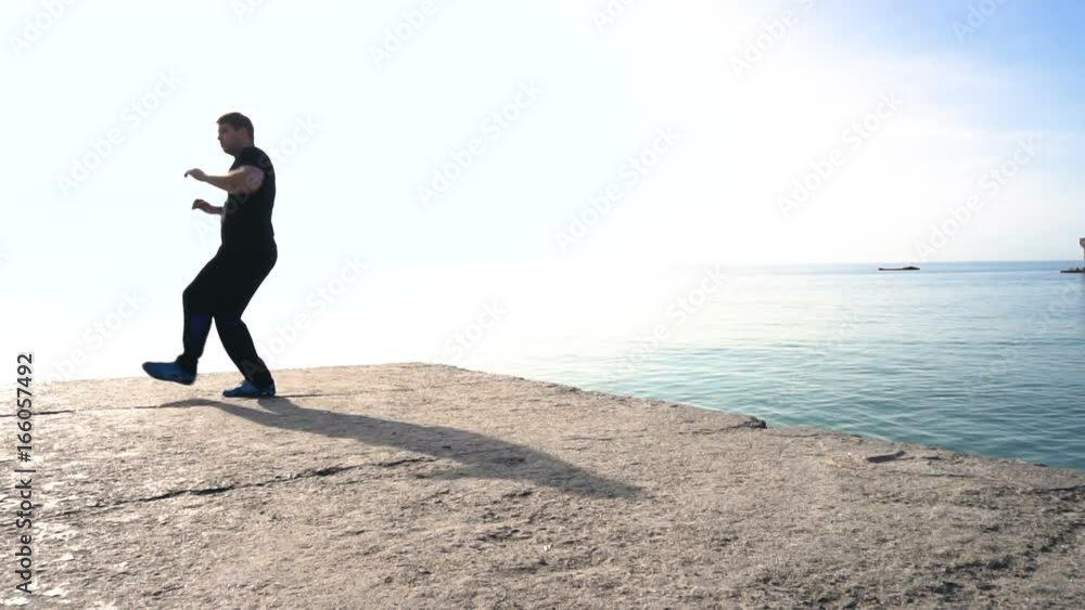 Young man does round house high kicks barefooted against sunrise in slow motion Young man does round house high kicks barefooted against sunrise in slow motion