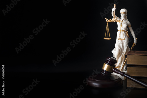 Legal code, enforcement of the law and blind Iustitia concept with statue of the blindfolded lady justice ( Dike in Greek and Justitia in Roman mythology), a stack of books, a gavel, and copy space