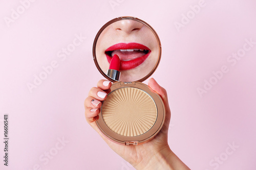 Closeup woman applying lipstick looking at mirror. Red lips