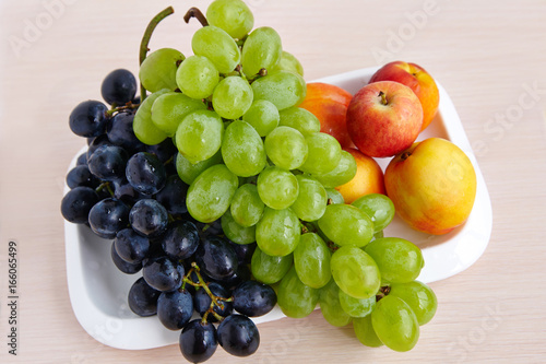A bunch of white and black grapes on a white plate