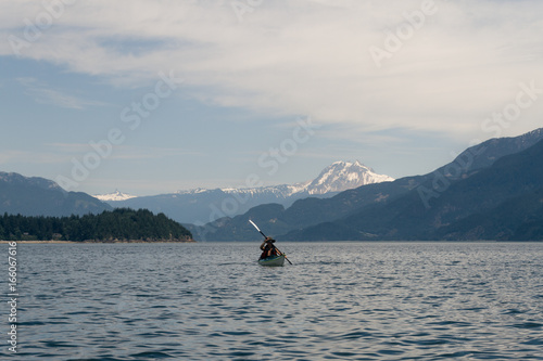 Lone kayaker on water with mountains in the background