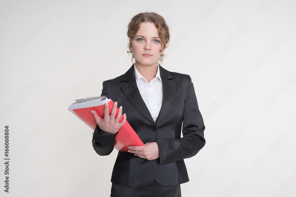 Businessman in a business suit with a red folder in his hands stands on a gray background Businessman in a business suit with a red folder in his hands stands on a gray background