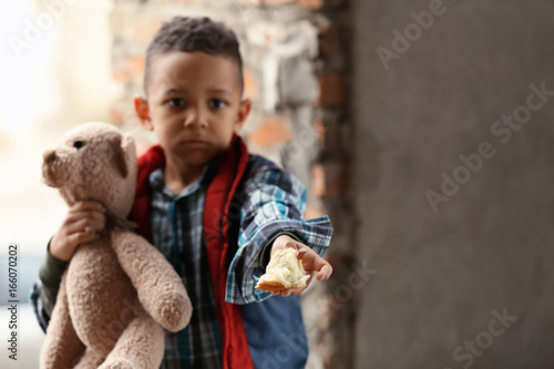 Fotografie Cute little boy with piece of bread in abandoned building