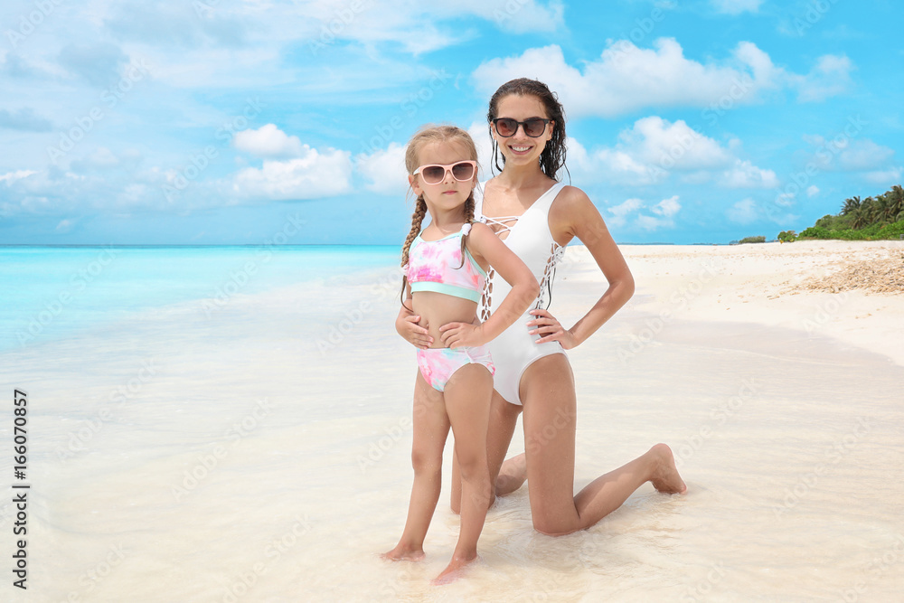 Beautiful young woman with her daughter on beach at sea resort