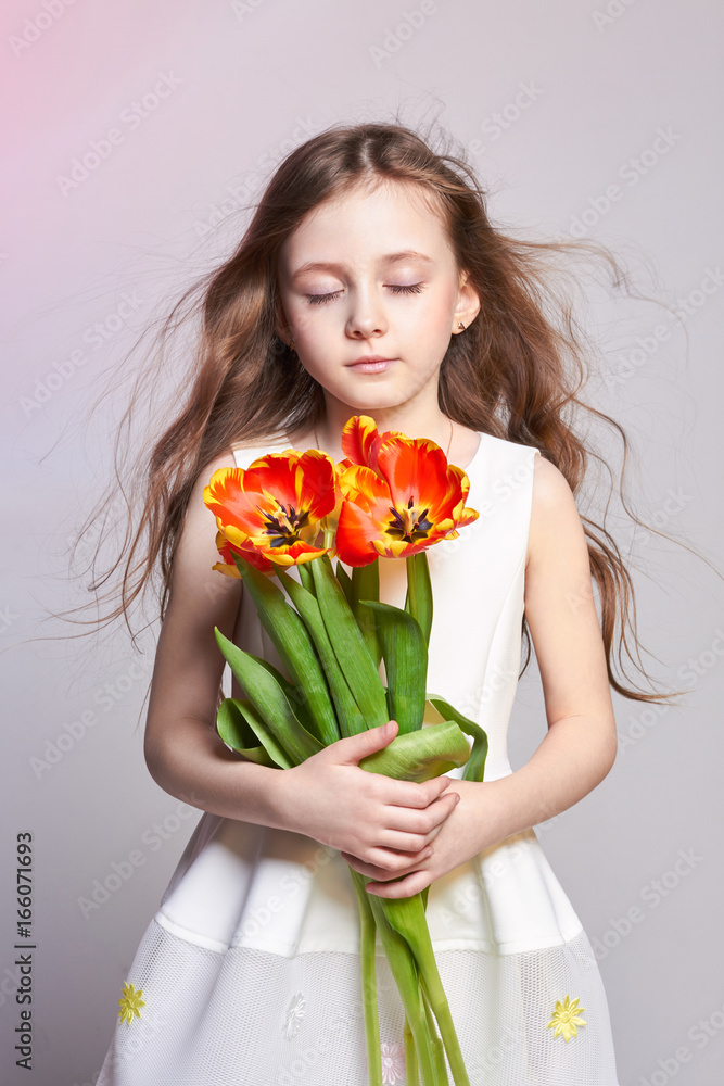 Fashion red-haired girl with tulips in hands. Studio photo on light coloured background. Birthday, holiday, mother's day, first day of school Fashion red-haired girl with tulips in hands. Studio photo on light coloured background. Birthday, holiday, mother's day, first day of school