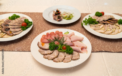 Cold meat plate with delicious sliced ham, prosciutto, meat and vegetables on celebratory dinner table, selective focus. Meat platter with selection