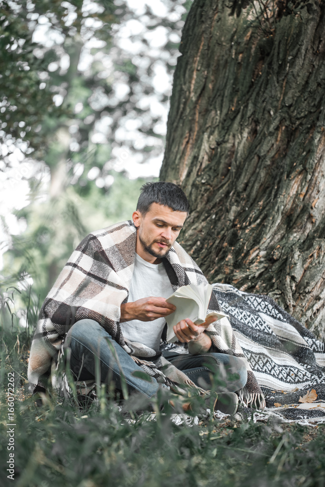 Obraz premium The young man at the tree reading a book
