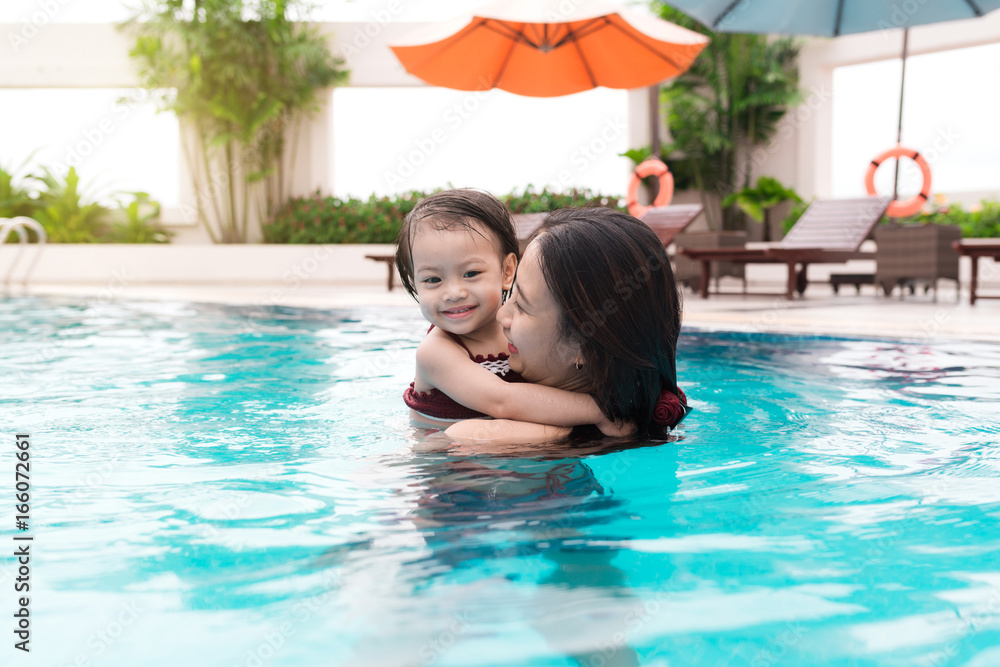 Mother and baby girl having fun in the pool. Summer holidays and vacation concept