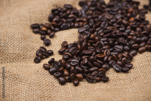 Fresh brown coffee beans on wooden background.