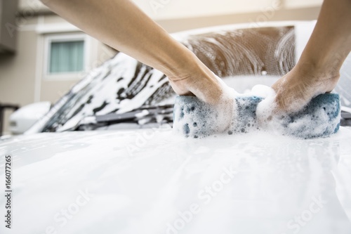 Using both hands to catch the sponge and rub on the bonnet with strength. Car wash concept