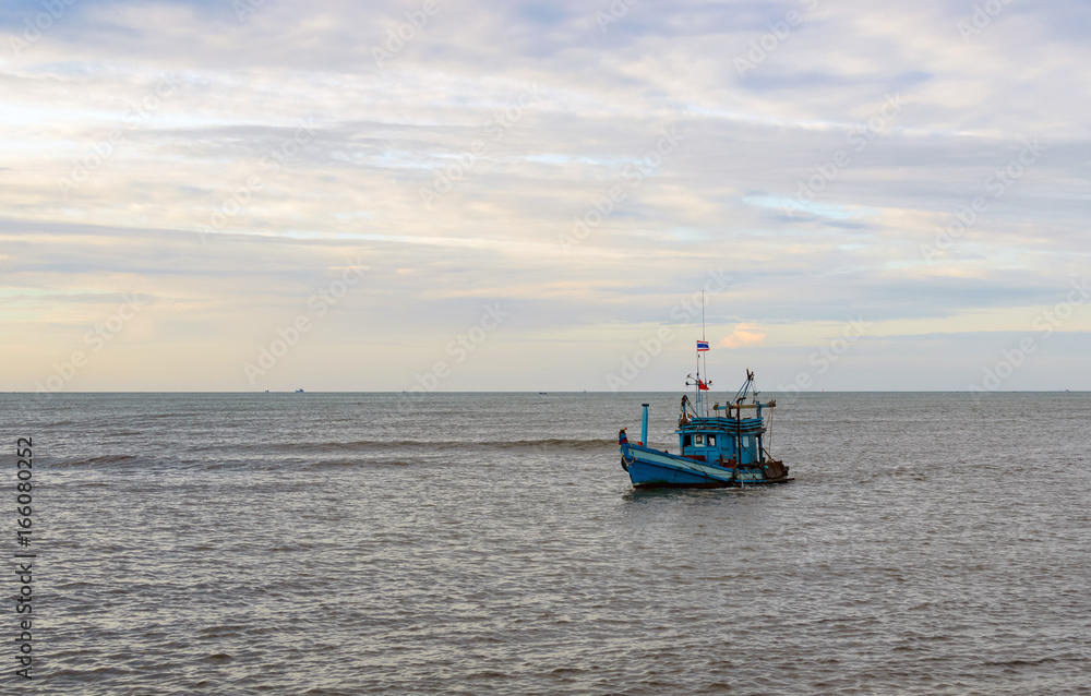 A lonely wooden fishing boat returns to the village after night catching at dawn