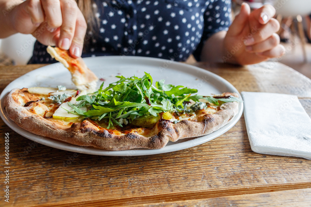 Four cheese pizza on a white plate with rucola lettuce