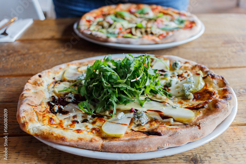 Four cheese pizza on a white plate with rucola lettuce