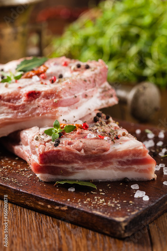 Raw pork ribs, on a plate sprinkled with spices.