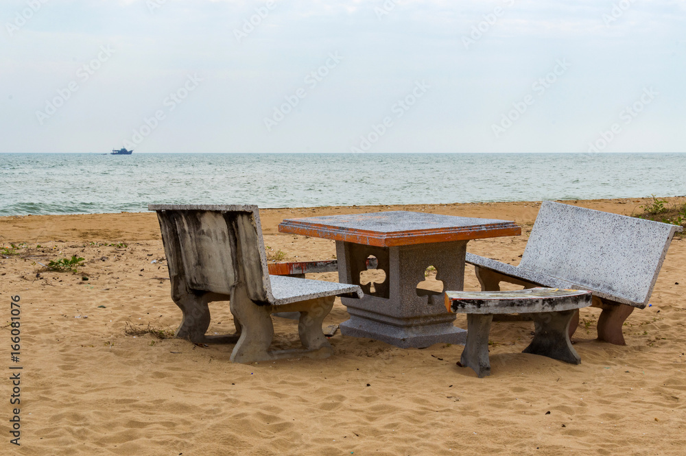 Patio with stone furniture, chairs and table on sandy beach