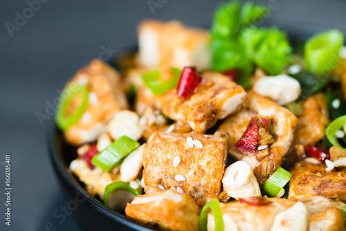 Stir fried tofu, cashew, chili on dark background. Close up