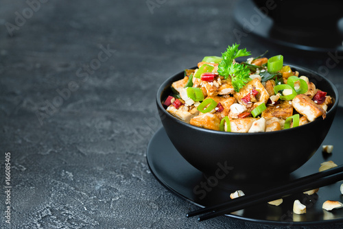 Stir fried tofu, cashew, chili on dark background. Copy space