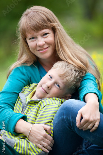 Portrait of European calm mother and son sitting and hugging together outdoor