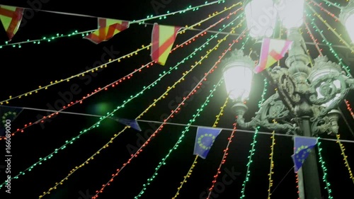 Camera movement from streetlight adronated by parties to flags and ornaments, illuminated at night photo