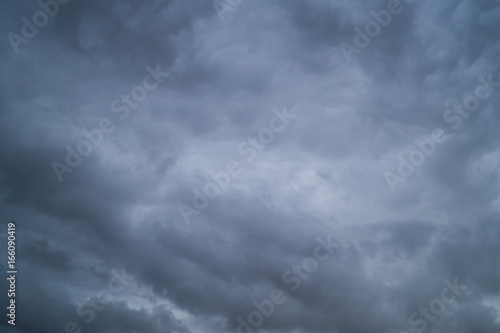 Grey dark fkuffy clouds on the blue sky at sunset or sunrise