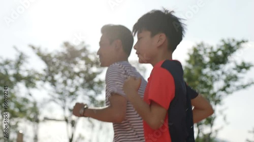 asian father & son jogging in the morning in garden back lit