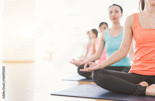 Time for yoga. Attractive young Asian woman group exercising and sitting in yoga lotus position in yoga classes Breath control