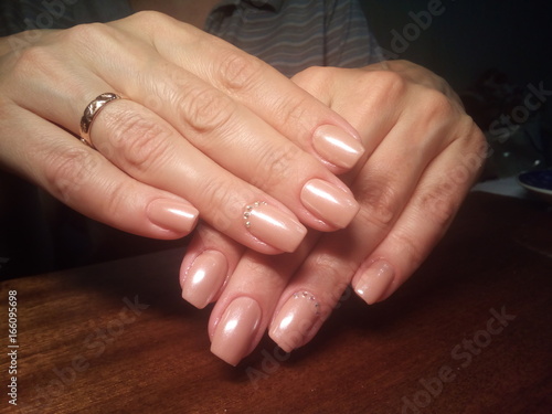 The manicurist excellently made her work a beautiful manicure with a polish gel on her hands and the client is happy