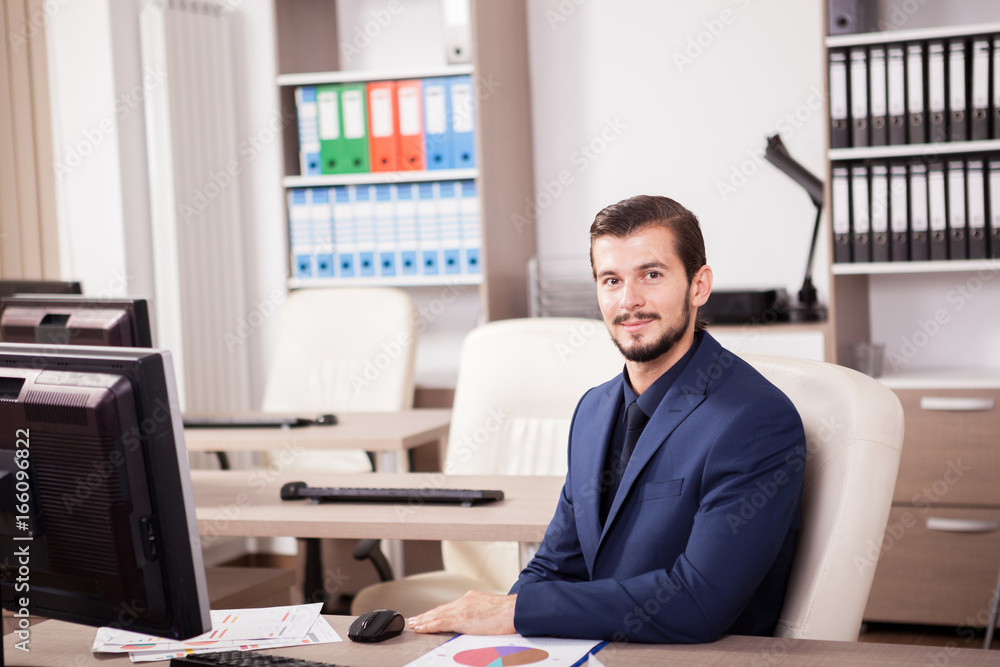 Naklejka premium Young Businessman in suit working in his office. Business and corporate. Image of young succesful entrepreneur at his work place.