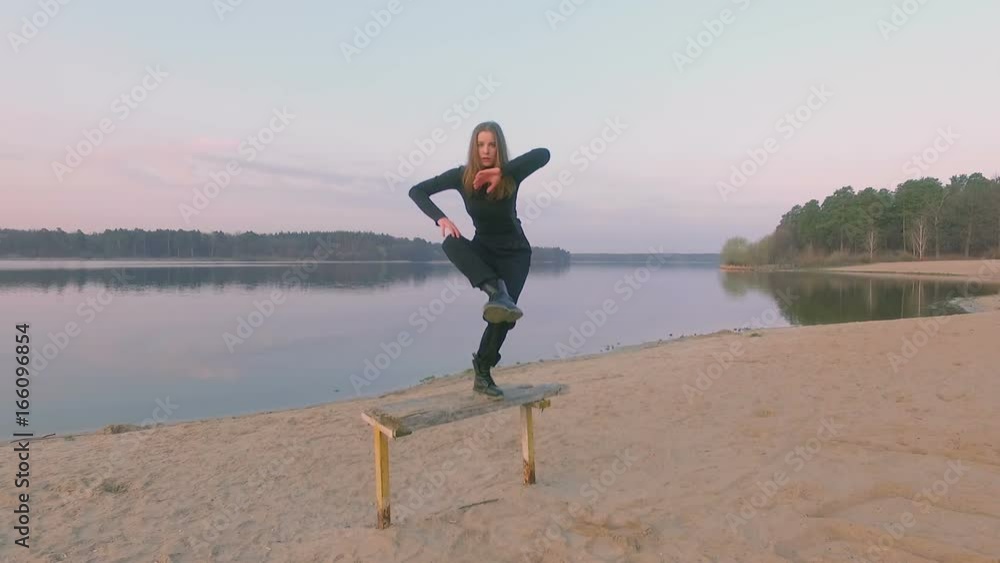 Young beautiful girl in black clothes dancing, at riverside Young beautiful girl in black clothes dancing, at riverside