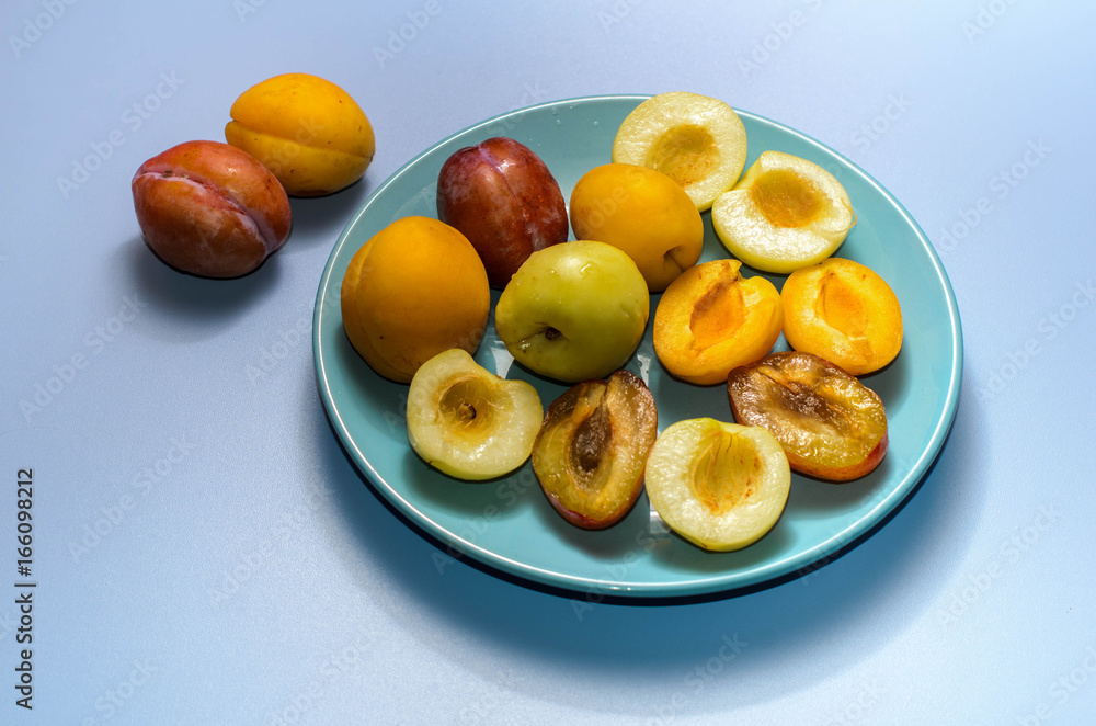 Summer fruits: apples, pears, apricots, plums on a blue plate