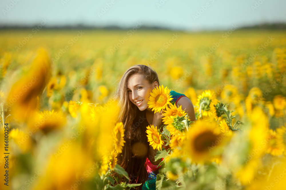 Young woman among yellow sunflowers in a field. Young woman among yellow sunflowers in a field.