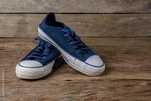 Blue canvas shoes on wooden background with copy space.