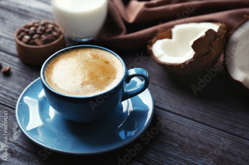 Cup with drink and ingredients for coconut coffee on wooden table