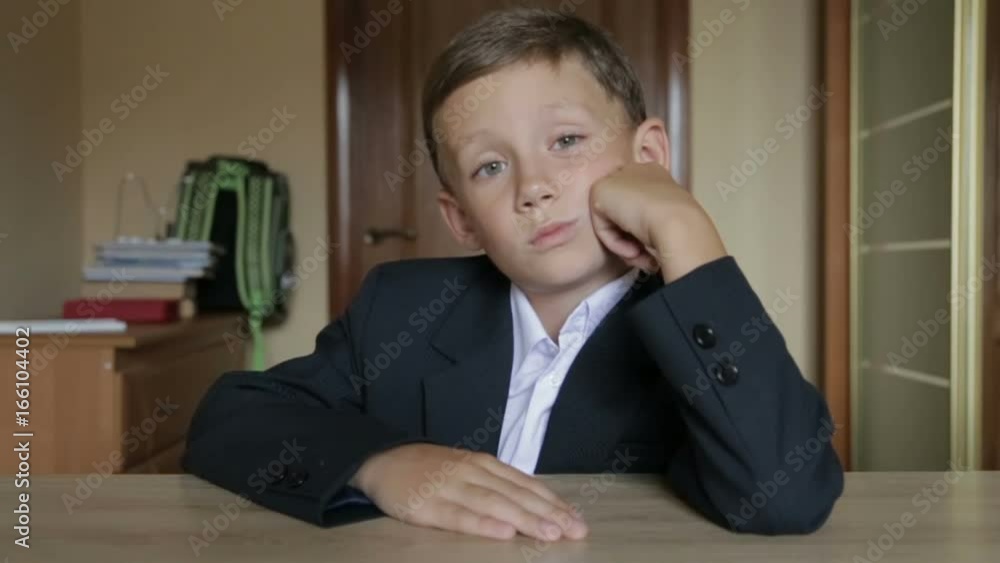 A pupil in school uniform sits at a desk A pupil in school uniform sits at a desk
