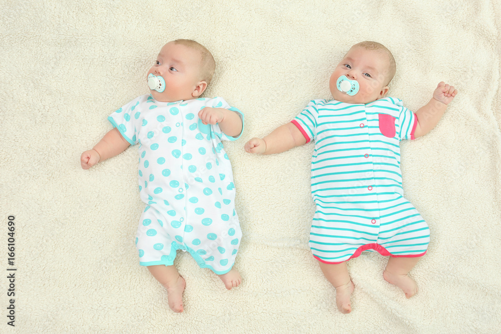Beautiful baby twins lying with pacifiers on plaid Beautiful baby twins lying with pacifiers on plaid