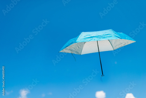 A blue umbrella flying on a blue sky