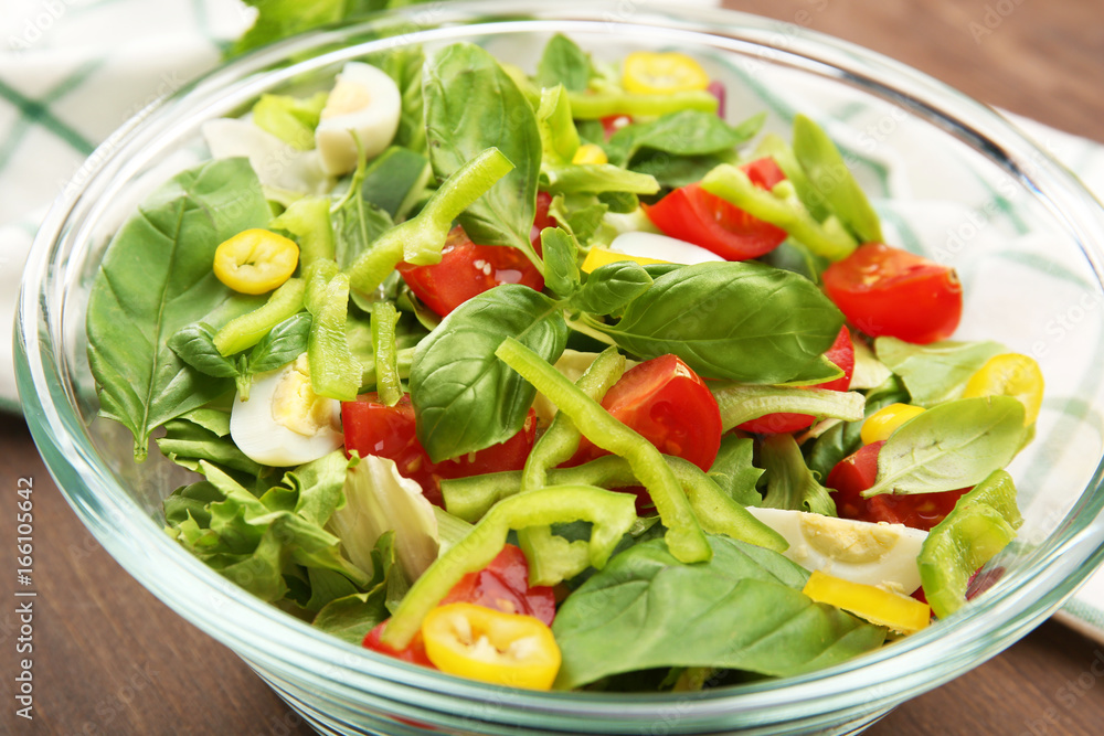 Glass bowl of fresh vegetable salad on wooden table Glass bowl of fresh vegetable salad on wooden table