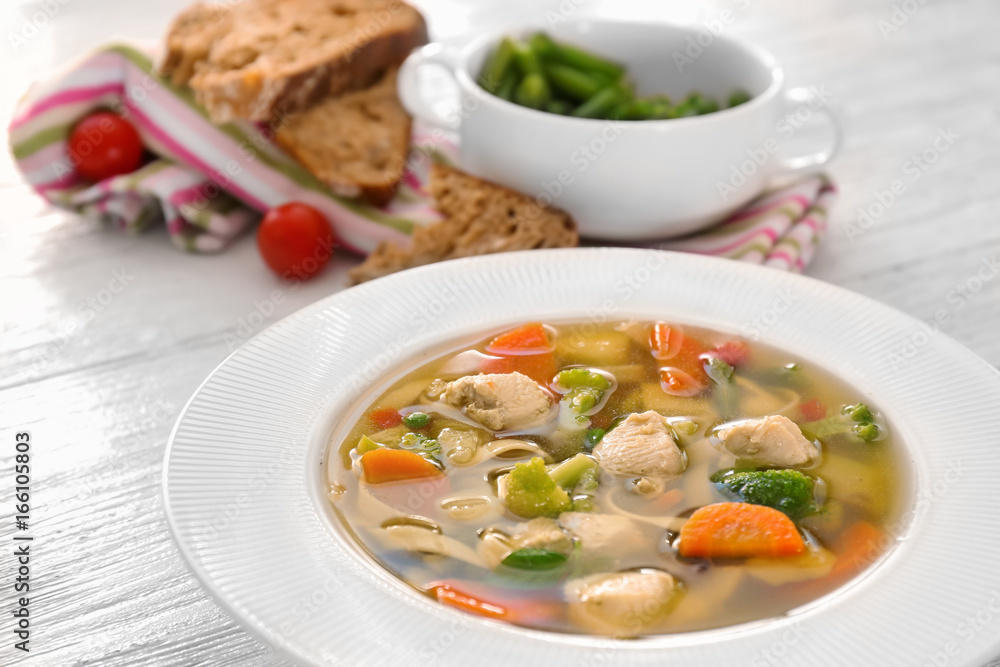 Plate with delicious turkey soup on wooden background