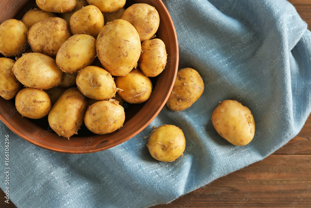 Bowl with raw organic potato on wooden table Bowl with raw organic potato on wooden table