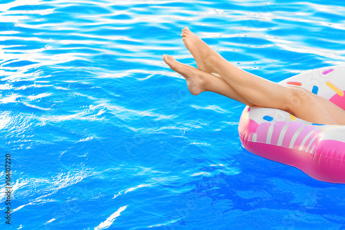 Young woman relaxing on inflatable donut in swimming pool