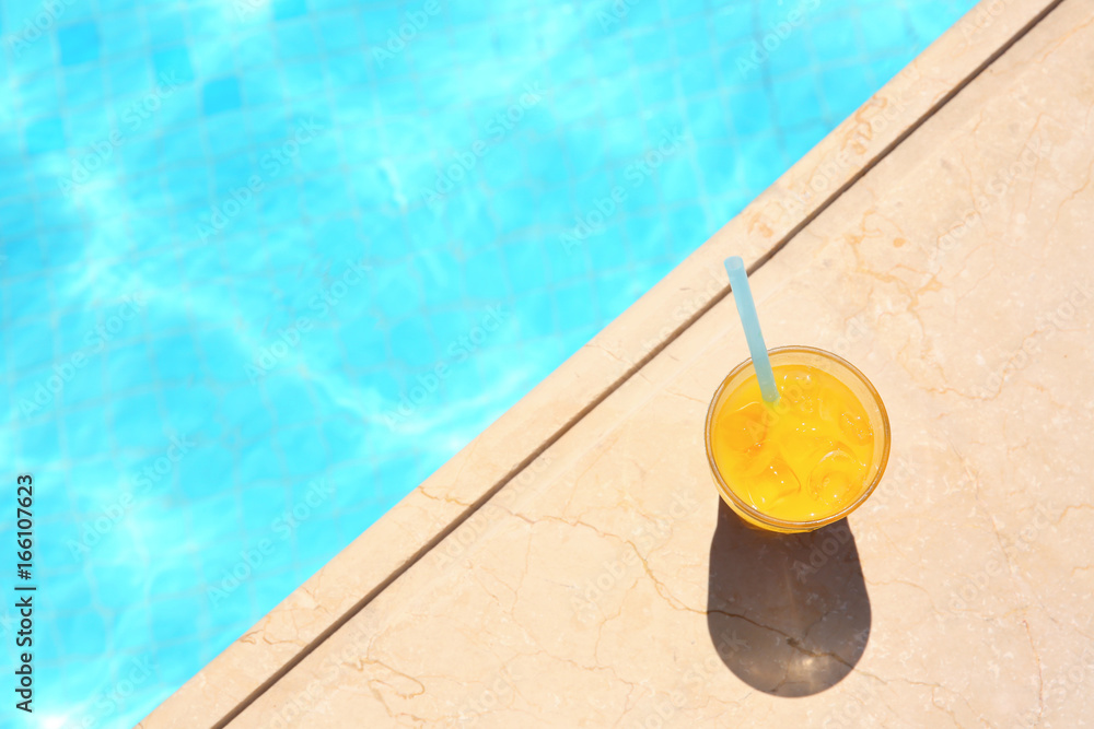 Obraz premium Tasty refreshing cocktail on edge of swimming pool