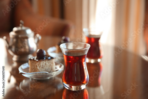 Turkish tea in traditional glass with dessert on table