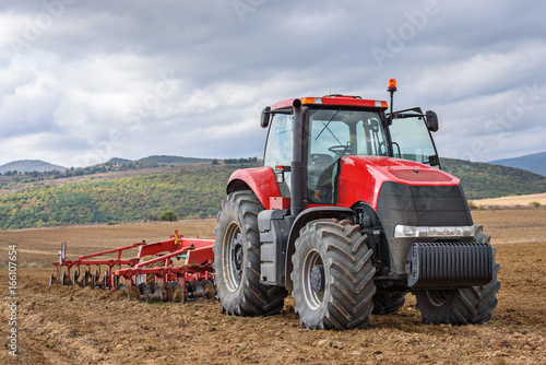 Farmer in tractor preparing farmland for seedbed.
