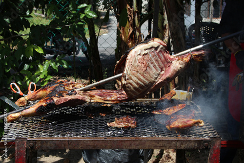 Close up of delicious whole lamb chop meat pieces on a grill under flames. Kambing Golek for Aqiqah photo