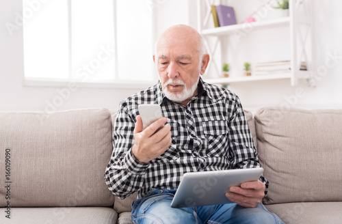Senior man using phone and tablet
