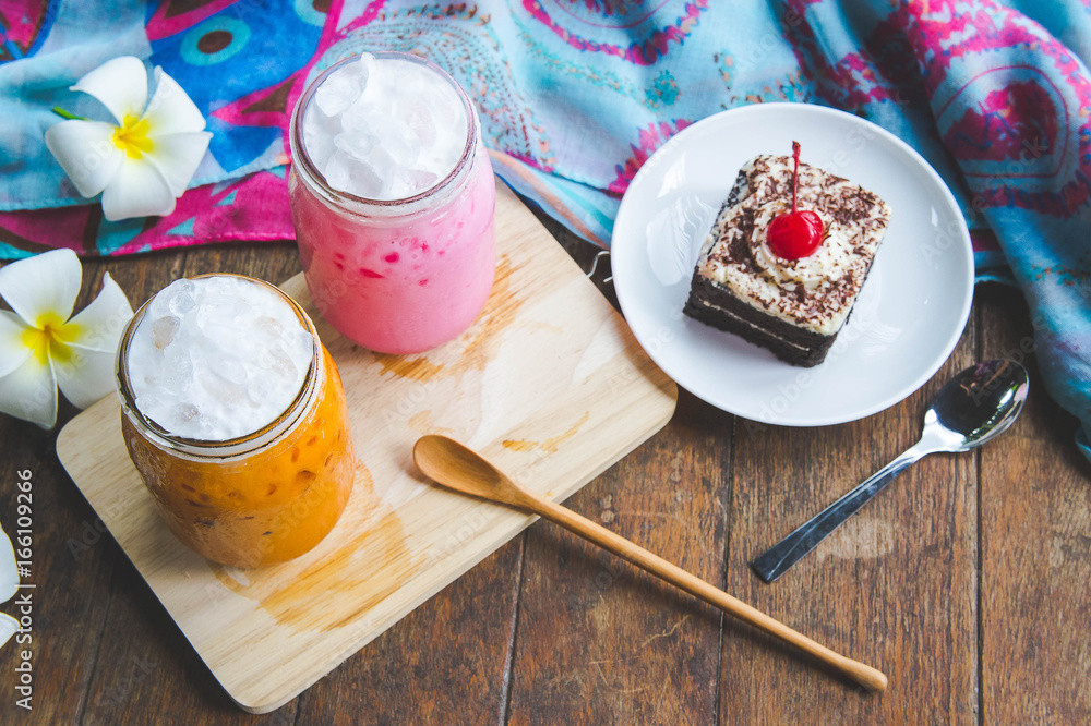 thai tea milkshake and pink milkshake beverage and cake chocolate dessert on wood table thai tea milkshake and pink milkshake beverage and cake chocolate dessert on wood table