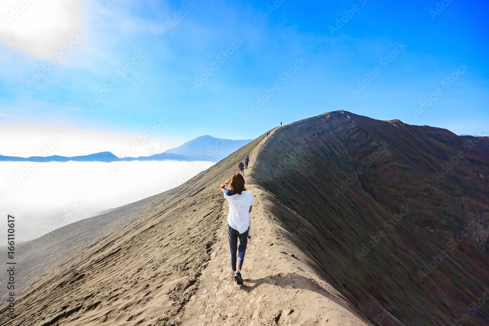 Female tourist walking through on the craters of Gunung Bromo and Sumeru volcanoes in Java, Indonesia