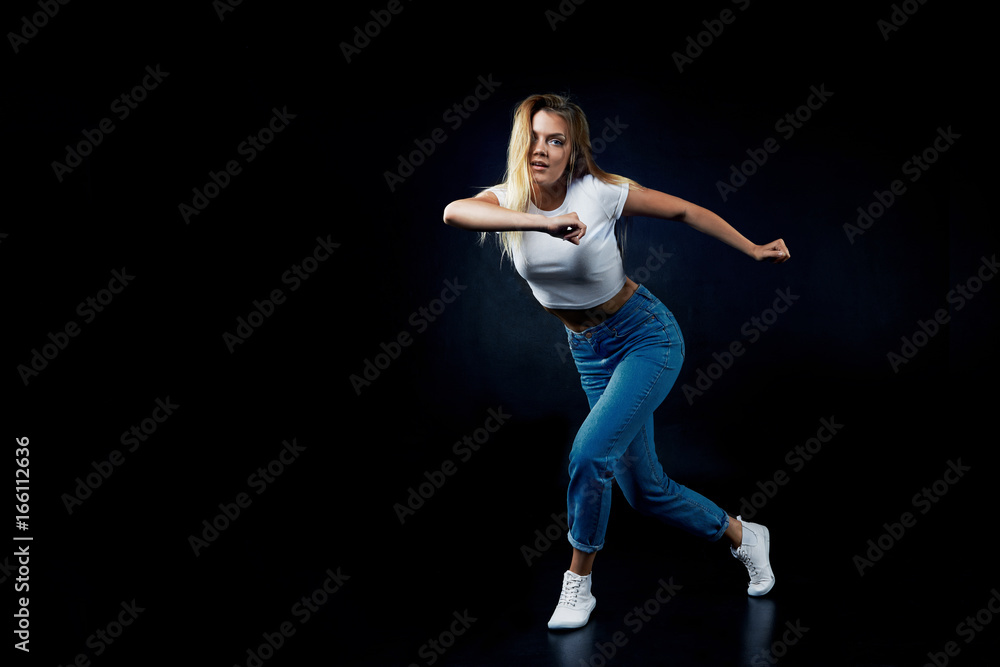 Indoor portrait of attractive confident female modern dancer doing dance pose while working out in studio, looking at camera, feeling tired but happy. Pretty girl showing dance improvisation Indoor portrait of attractive confident female modern dancer doing dance pose while working out in studio, looking at camera, feeling tired but happy. Pretty girl showing dance improvisation