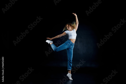Picture of amazing agile talented young Caucasian female dancer wearing sneakers and sensible clothes demonstrating her skills in dance improvisation, dancing with eyes closed, feeling free